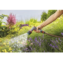 Een persoon besproeit een tuin met een Gardena tuinspuit.