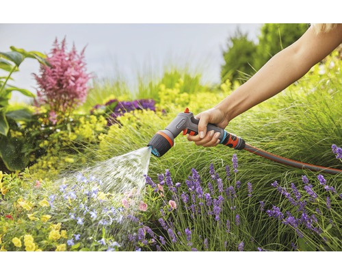 Een persoon besproeit een tuin met een Gardena tuinspuit.
