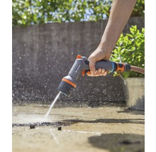 Iemand gebruikt een Gardena multifunctionele spuitkop om een oppervlak water te geven.