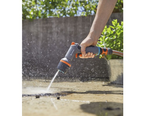 Iemand gebruikt een Gardena multifunctionele spuitkop om een oppervlak water te geven.