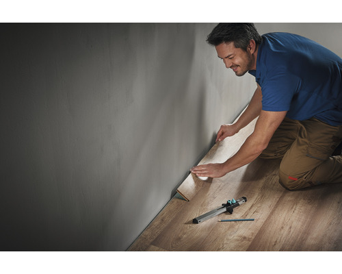 Man legt laminaat met gereedschap langs een muur