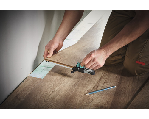 Persoon legt laminaat met een markeergereedschap.