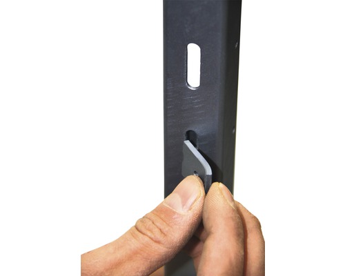 Detailopname van een metalen stellingframe met een hand die een grijze wig plaatst. De afbeelding toont de montage van een stelling.