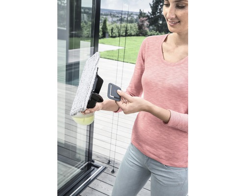 Een vrouw maakt een glazen ruit schoon met een ruitenreiniger.