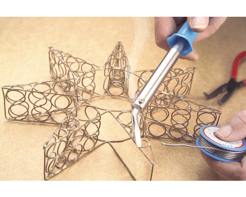 Soldeerwerkzaamheden aan een metalen ster met soldeerbout en soldeerdraad.