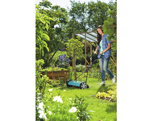 Vrouw gebruikt handgrasmaaier in de tuin