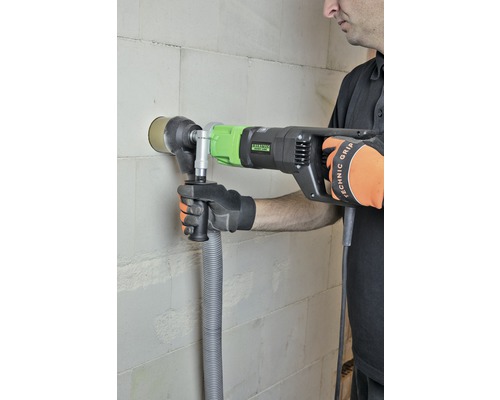 Een man boort met een muurdoorbraakzaag een gat in een muur.