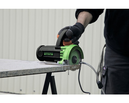 Een hand bedient een Eibenstock tegelsnijmachine om een tegel te snijden.