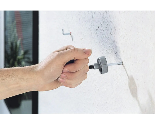 Een persoon bevestigt een plug met een montagegereedschap aan een muur