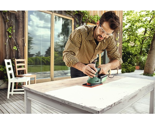 Man schuurt een tafelblad buiten met een schuurmachine