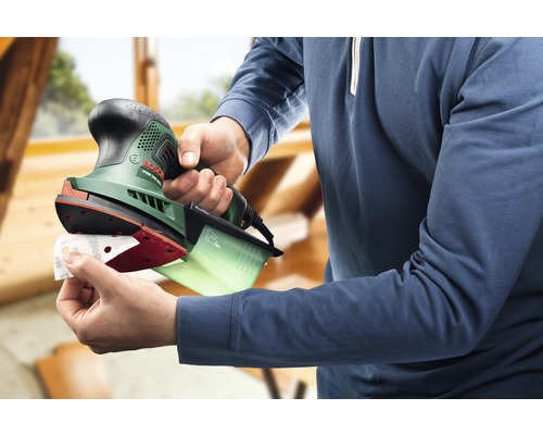 Een persoon bevestigt schuurpapier aan een vlakschuurmachine voor houtbewerking.