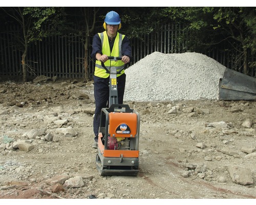 Bouwvakker verdicht grond met een trilplaat.