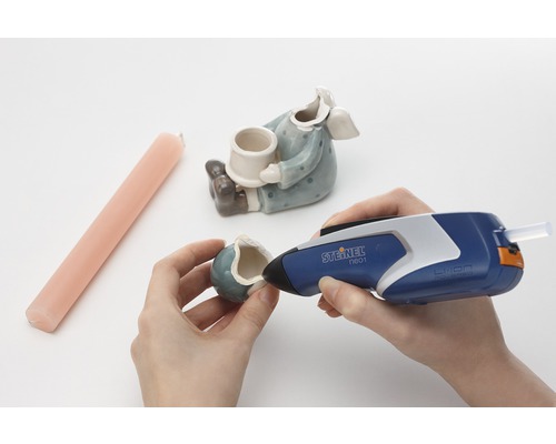 Persoon repareert een keramische figuur met een lijmpistool van Steinel.