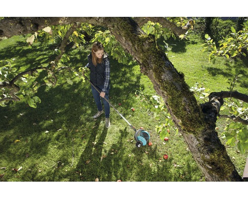Vrouw gebruikt fruitverzamelaar in de tuin onder een boom.