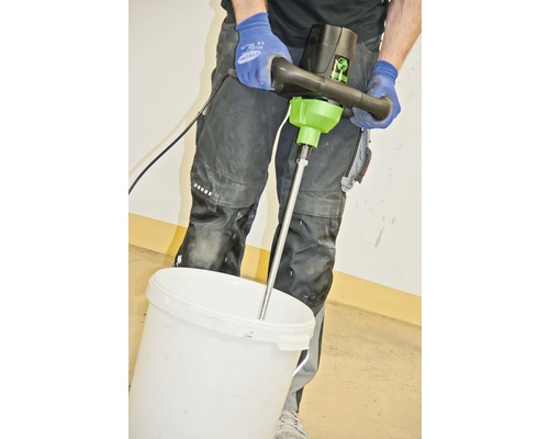 Man mengt materiaal met een verfmixer in een emmer.