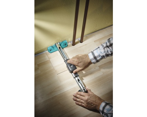 Persoon legt laminaat met een trekijzer langs een muur.