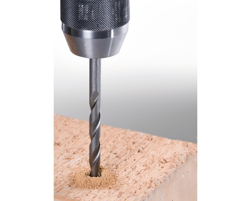 Close-up van een boor die in een baksteen boort.