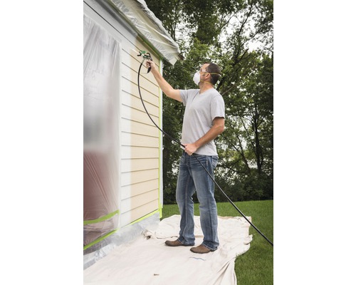 Man schildert huisgevel met verfspuit