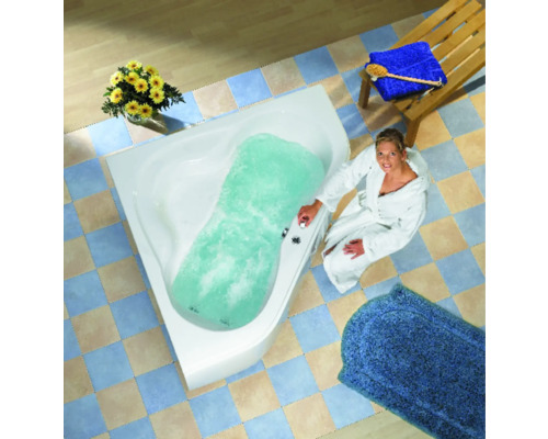 Vrouw in badjas naast gevuld hoekbad met bubbelbadfunctie in badkamer