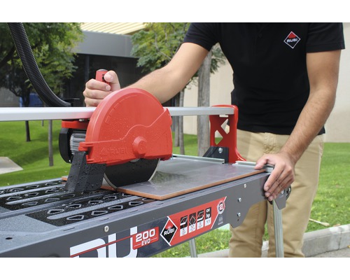 Tegelsnijder in gebruik met operator die een tegel snijdt.