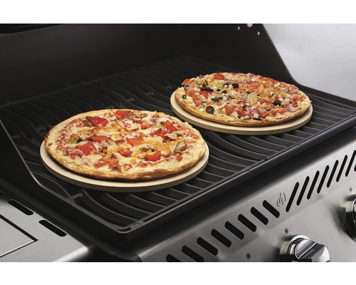 Twee pizza''s op pizzastenen op een grill.