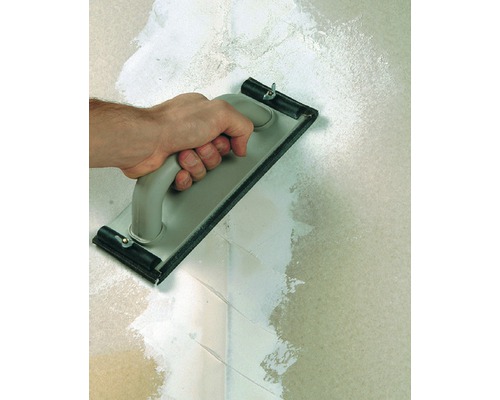 Hand met pleisterbord bij het aanbrengen van pleister op een muur