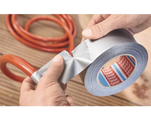 Een persoon repareert een slang met ducttape. Tesa Logo.