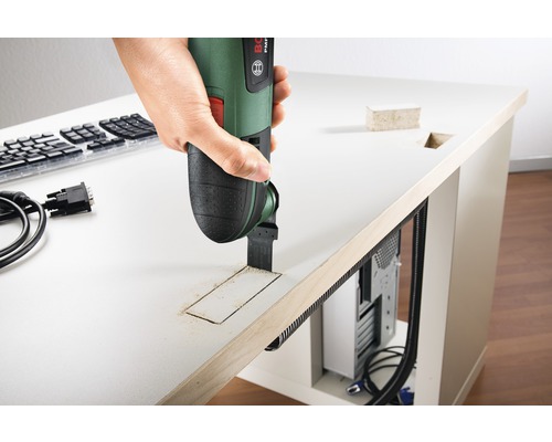 Een persoon gebruikt een multifunctioneel gereedschap om een gat in een tafelblad te zagen.