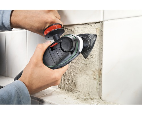 Een persoon gebruikt een multifunctioneel gereedschap om voegmiddel van tegels te verwijderen.