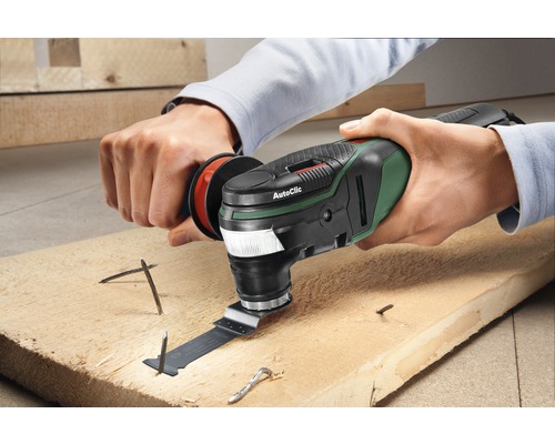 Een persoon gebruikt een multifunctioneel gereedschap op een houten plank met spijkers.