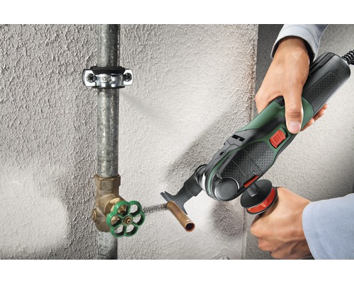 Oscillerend elektrisch gereedschap dat een koperen buis doorsnijdt op een muur