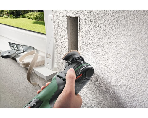 Persoon gebruikt multifunctioneel gereedschap om in een muur te snijden