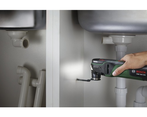 Bosch multitool die een gat snijdt in een badkamerkast onder een wastafel