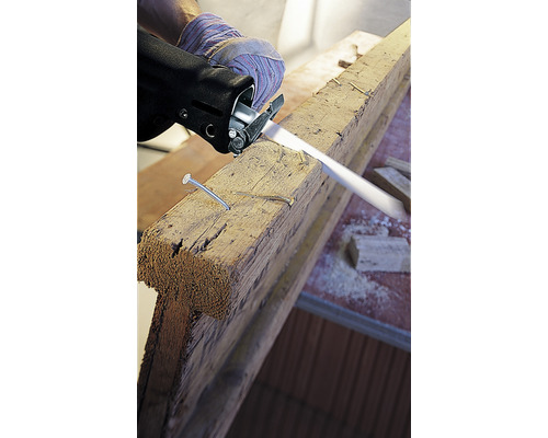 Een decoupeerzaag snijdt een houten plank met spijkers.