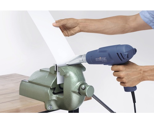 Iemand buigt kunststof met een heteluchtpistool en een bankschroef.