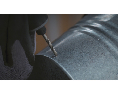 Een persoon boort een gat in een gegalvaniseerde buis.