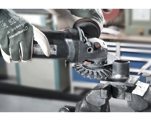 Ambachtsman met beschermende handschoenen en haakse slijper bij metaalbewerking in een werkplaats