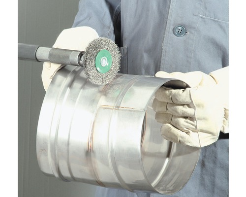 Een persoon gebruikt een staalborstel om een metalen buis schoon te maken.