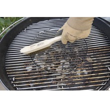 Een persoon maakt een grillrooster schoon met een draadborstel.