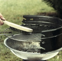 Grillborstel reinigt een ronde houtskoolgrill