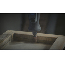 Een Dremel schuurgereedschap wordt gebruikt op een houten frame.