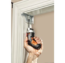 Een persoon schroeft met een accuschroevendraaier een beugel aan een deurkozijn vast.