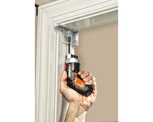 Een persoon schroeft met een accuschroevendraaier een beugel aan een deurkozijn vast.