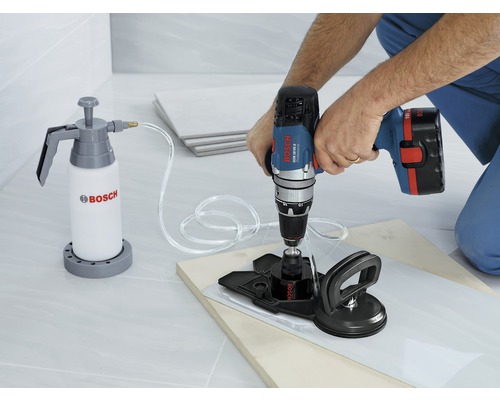 Een tegel boren met een boormachine, een waterreservoir en een zuignap