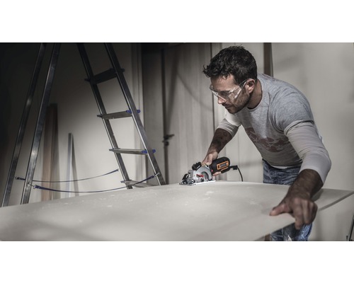 Man zaagt houten plaat met handcirkelzaag in werkplaats