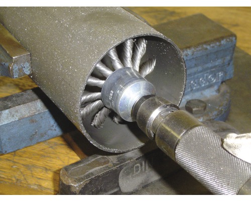 Draadborstel in gebruik voor het ontbramen van een metalen buis