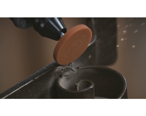 Een schuurgereedschap op een metalen werkstuk.