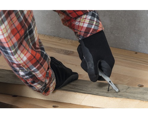 Persoon verwijdert een spijker uit een houten plank met een spijkerverwijderaar