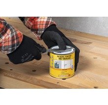 Iemand met handschoenen opent een blik PU Acryl raam- en deurlak met een gereedschap van het merk Hornbach.