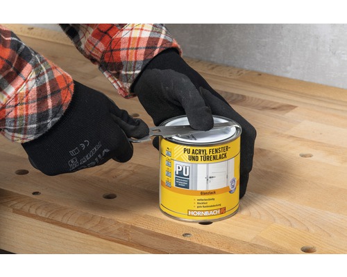 Iemand met handschoenen opent een blik PU Acryl raam- en deurlak met een gereedschap van het merk Hornbach.